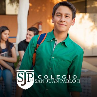 Estudiante con camisa verde sonriendo en patio escolar con logotipo del Colegio San Juan Pablo II