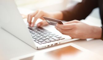 Persona realizando una compra online con tarjeta de crédito en laptop
