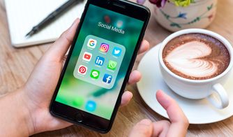 Smartphone con aplicaciones de redes sociales junto a una taza de café