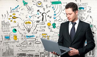 Ejecutivo con laptop frente a mural de ideas y gráficos