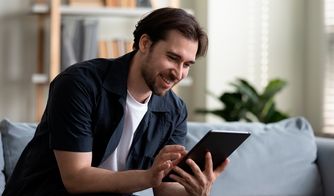 Hombre sonriente utilizando una tablet en el sofá