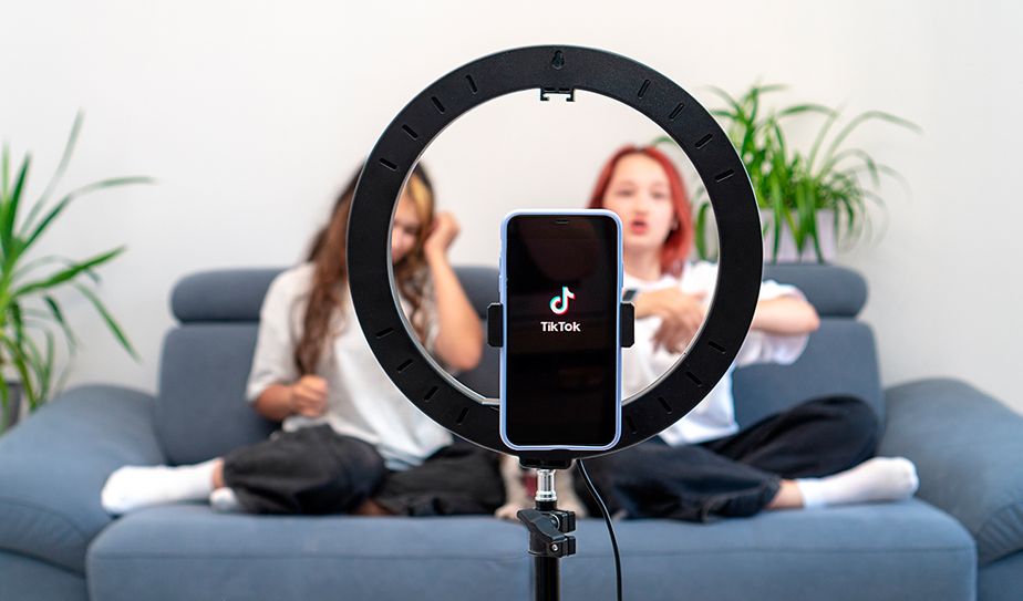El auge de los creadores de contenido en TikTok Teléfono grabando un video de TikTok frente a dos jóvenes