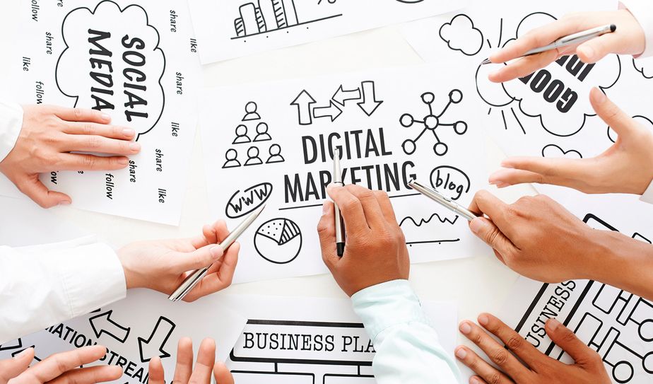 Manos colaborando sobre esquemas de marketing digital