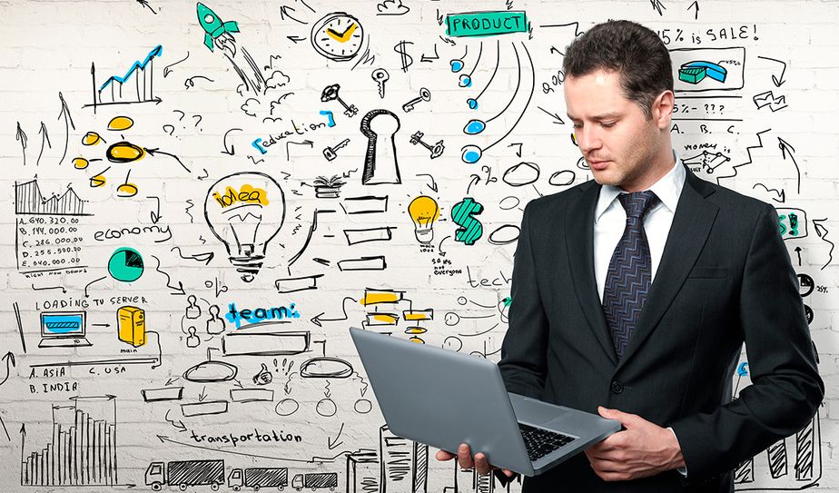 Ejecutivo con laptop frente a mural de ideas y gráficos