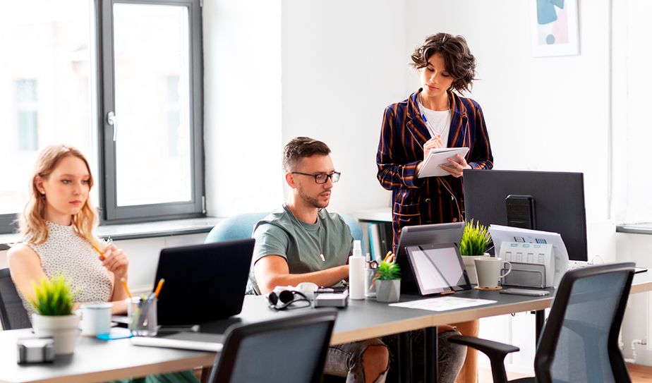Personas trabajando en una oficina moderna con computadoras y plantas